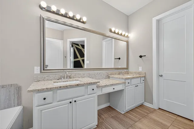 a bathroom with a granite countertop sink mirror and a bath tub
