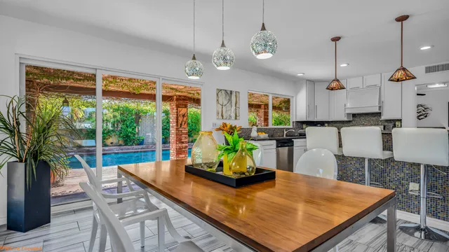 a view of a patio with table and chairs potted plants and floor to ceiling window and potted plants