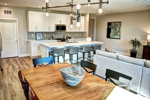 a view of a patio with couches table and chairs under an umbrella