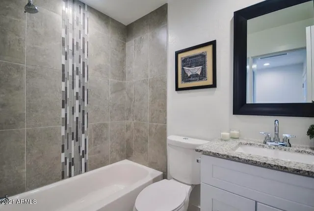 a bathroom with a granite countertop toilet a sink and mirror