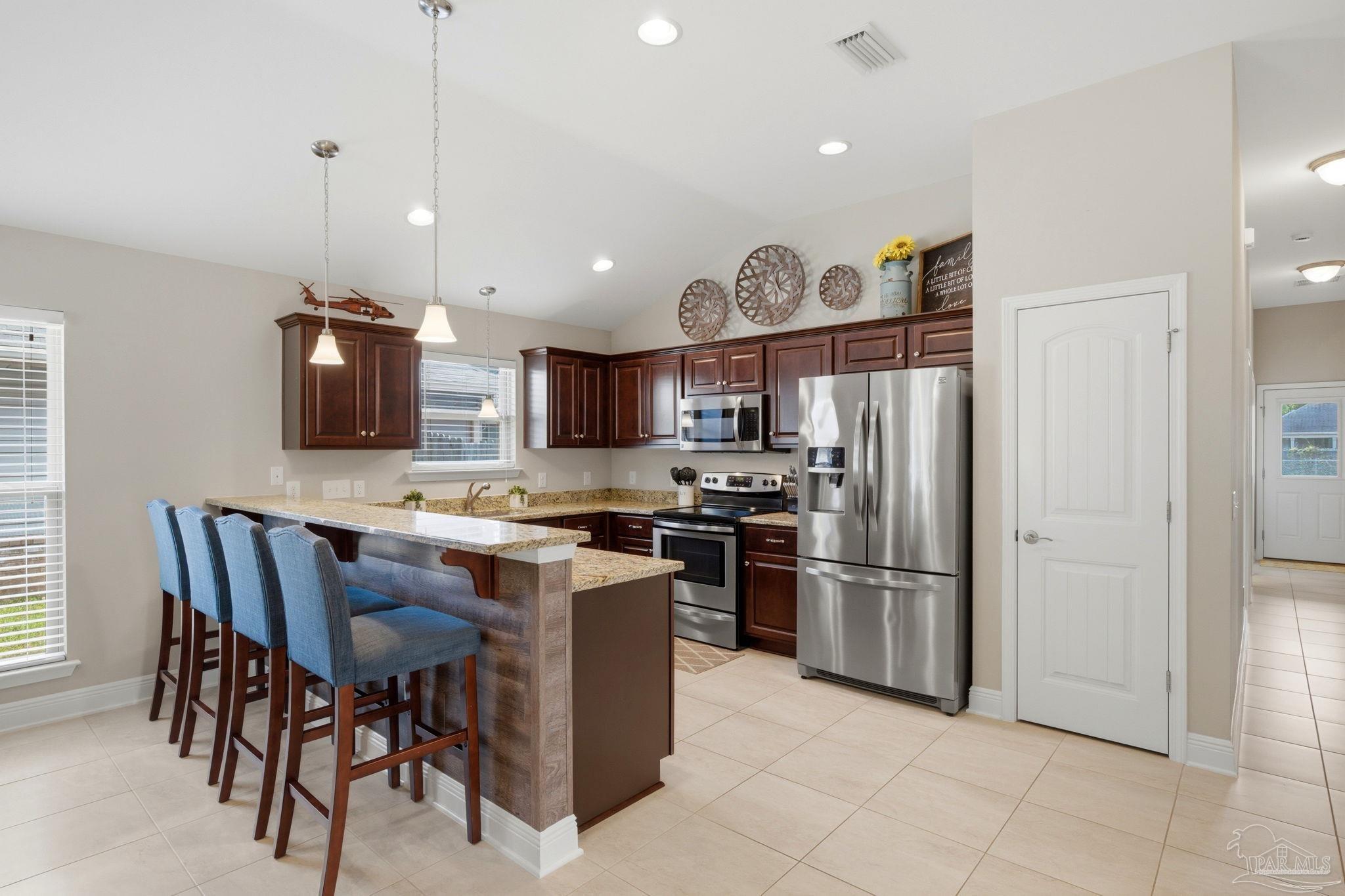 3859 Adams Road Pace, FL 32571 - Photo 9 of 26 a kitchen with stainless steel appliances granite countertop a refrigerator a sink dishwasher a dining table and chairs with wooden floor