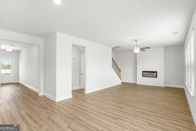 an empty room with wooden floor and ceiling fan
