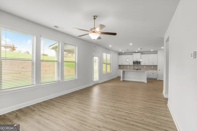 a view of an empty room with a kitchen and wooden floor