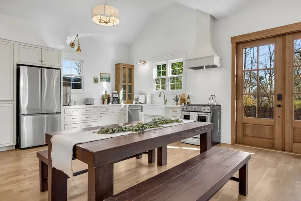 a kitchen with kitchen island a stove a refrigerator and a dining table with wooden floor