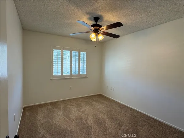 an empty room with a window and a fan