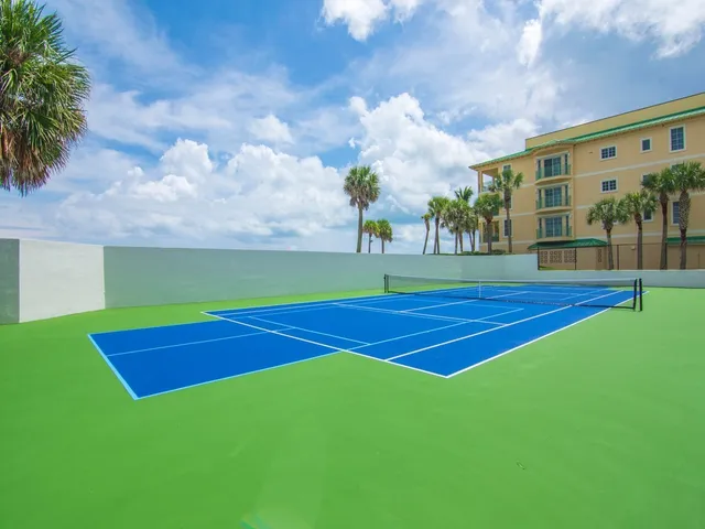 a view of a tennis ground with large trees