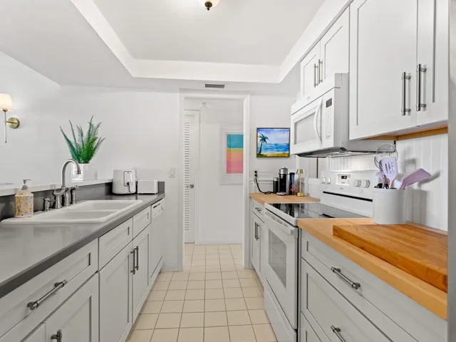 a kitchen with granite countertop a sink stainless steel appliances and white cabinets