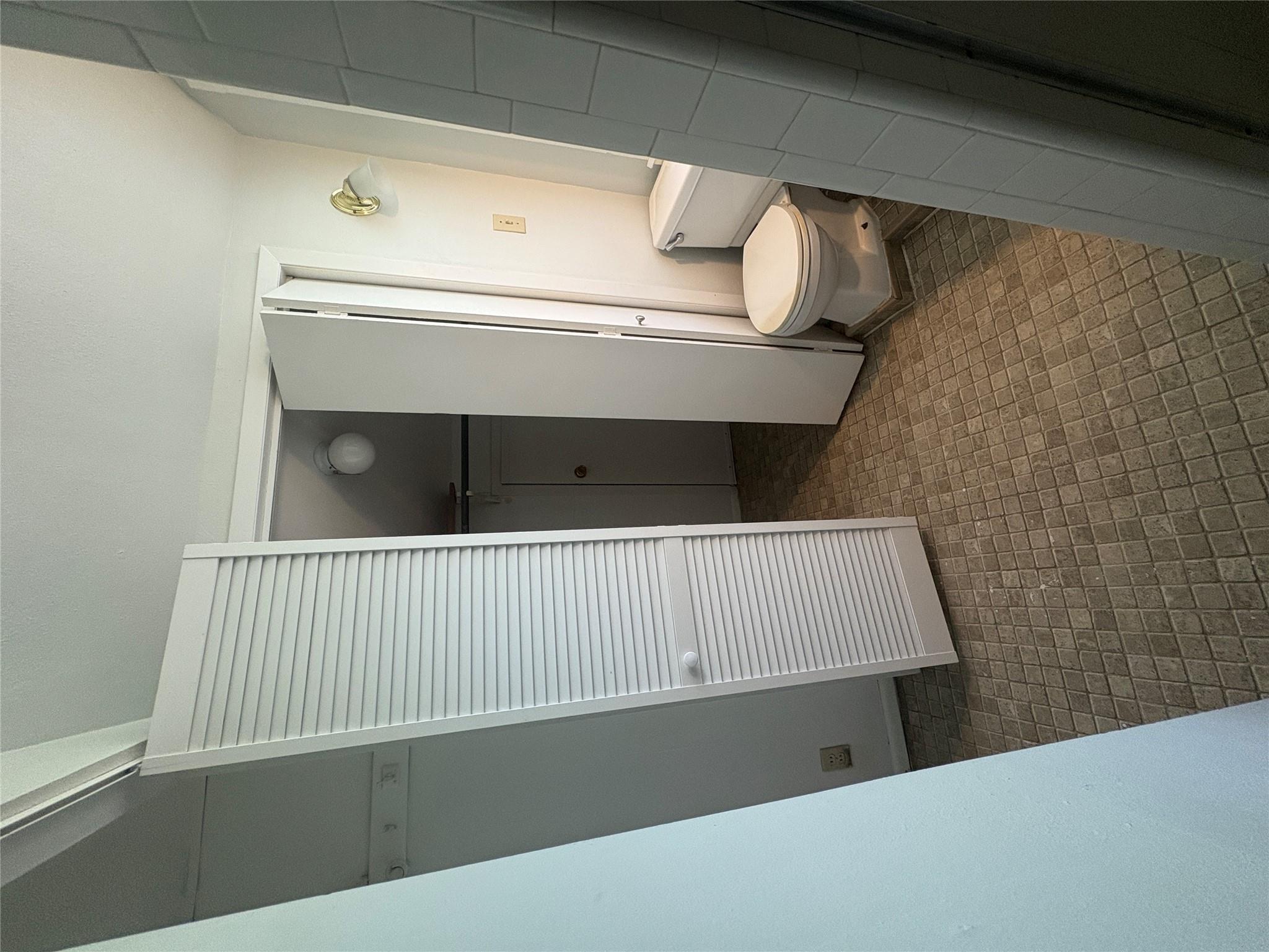 915 West 29th Street Austin, TX 78705 - Photo 18 of 20 Bathroom featuring patterned tile flooring, a white toilet, and a wall-mounted light fixture