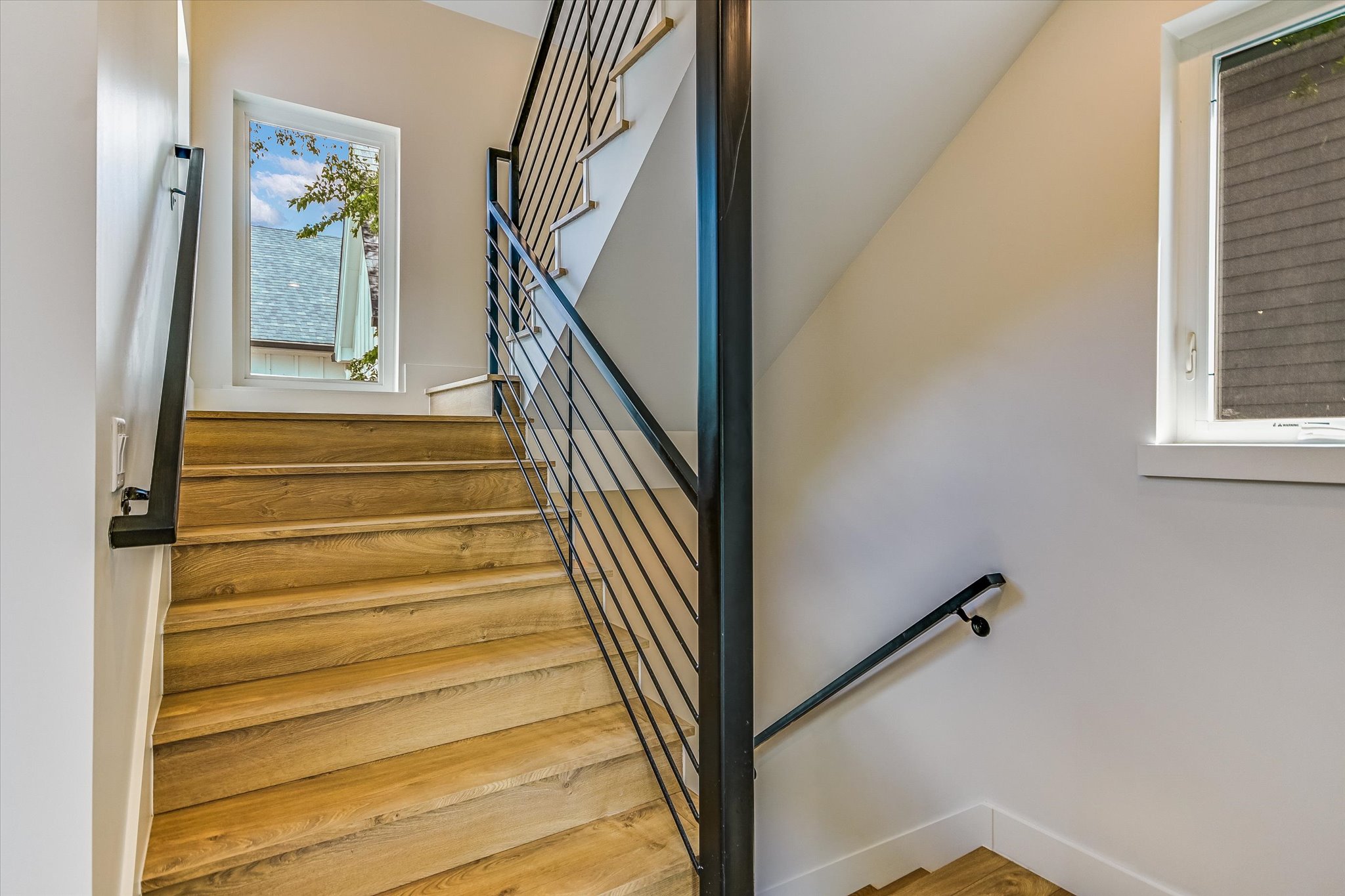 1605 Hether Street Austin, TX 78704 - Photo 22 of 26 Staircase featuring wood-finish treads, a contemporary black metal balustrade, and a window providing natural light