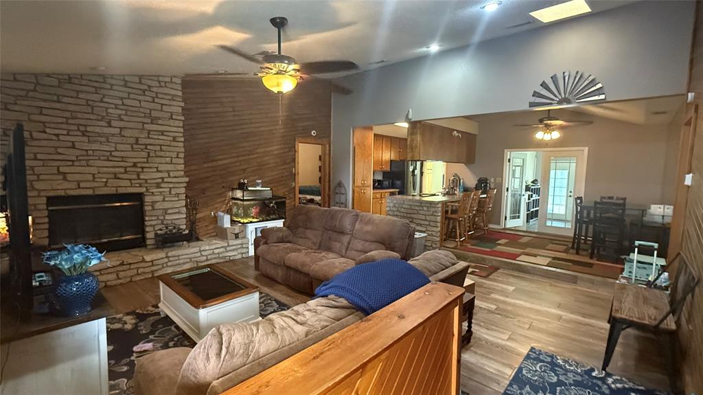1356 Kerry Lane Azle, TX 76020 - Photo 6 of 27 Spacious living area featuring a prominent stone fireplace, wood-finish flooring, and vaulted ceilings with skylights