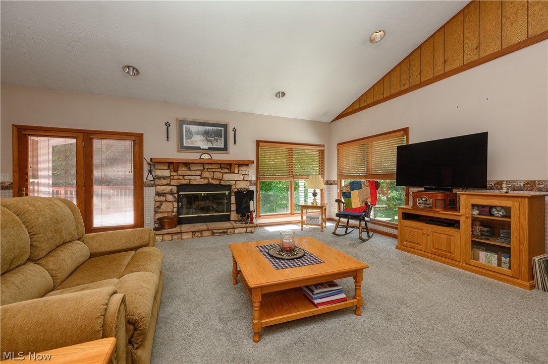 8745 Broadview Road Broadview Heights, OH 44147 - Photo 4 of 49 Spacious living area featuring a stone fireplace with a wood mantel, vaulted ceiling with wood paneling, and large windows