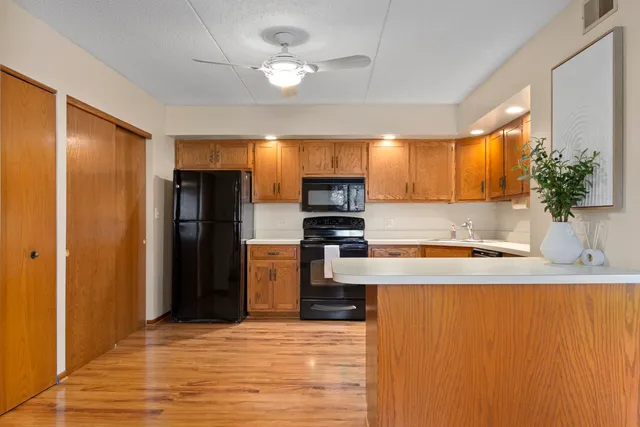 a kitchen with stainless steel appliances granite countertop a refrigerator a stove and a sink with wooden floor