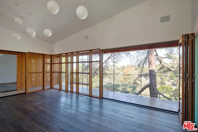 a view of an empty room with wooden floor and windows