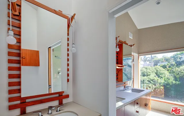 a bathroom with a granite countertop sink a mirror and shower
