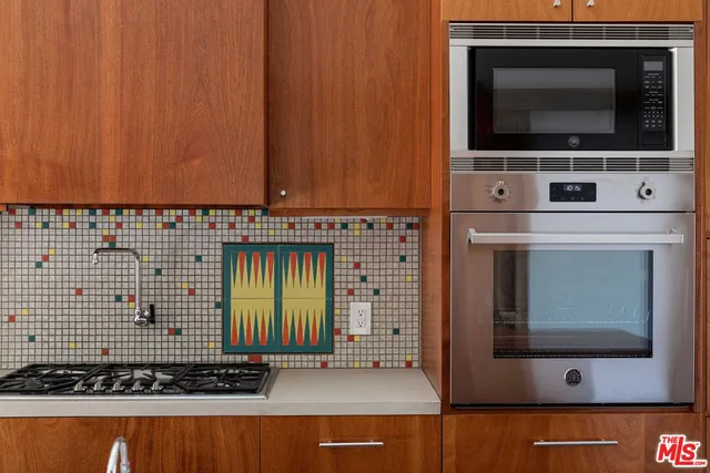 a kitchen with stainless steel appliances granite countertop a sink a stove top oven a counter space and wooden floor