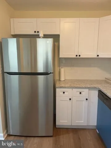 a kitchen with granite countertop a refrigerator a sink and dishwasher