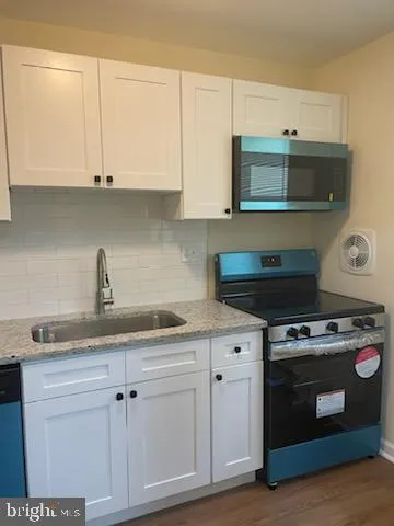 a kitchen with granite countertop white cabinets and stainless steel appliances