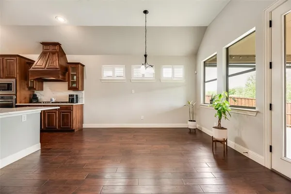 a view of a kitchen and an empty room with wooden floor