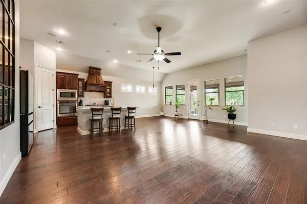 an empty room with wooden floor chandelier and windows