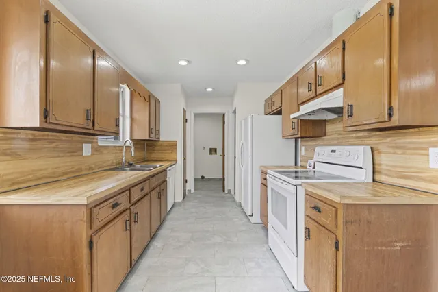a large kitchen with stainless steel appliances granite countertop a stove a sink and a refrigerator