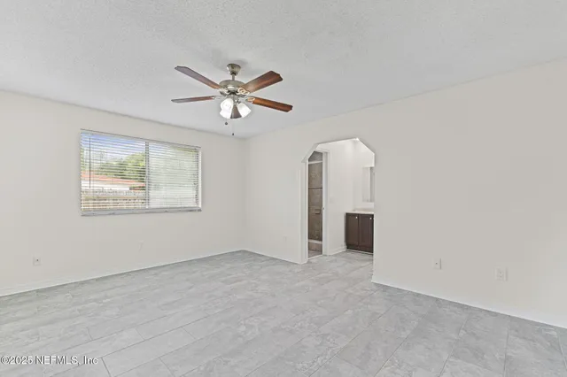 an empty room with chandelier fan and windows
