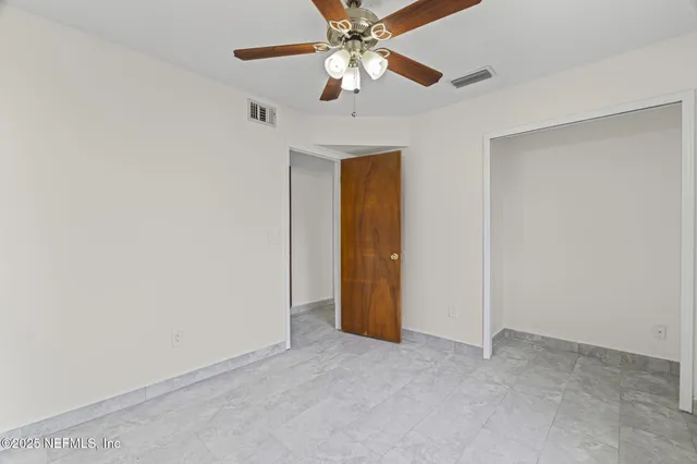 an empty room with closet and a chandelier fan