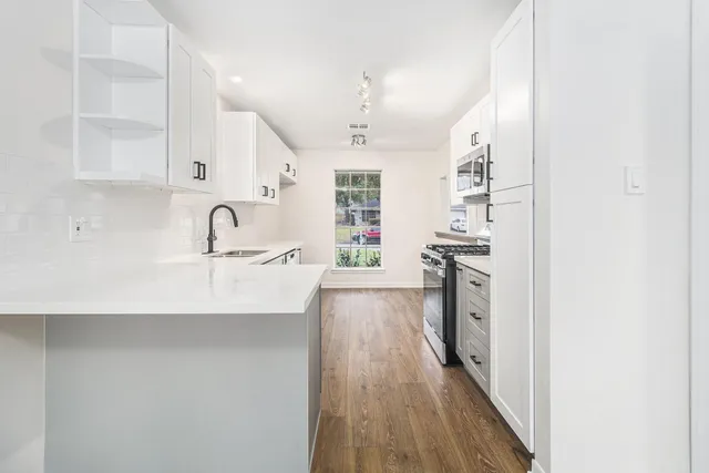 a kitchen with kitchen island a sink wooden floor and stainless steel appliances