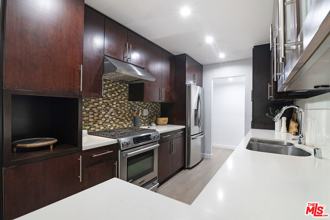 1887 Greenfield Avenue, Unit 110 Los Angeles, CA 90025 - Photo 6 of 18 a kitchen with stainless steel appliances kitchen island granite countertop a sink stove and refrigerator