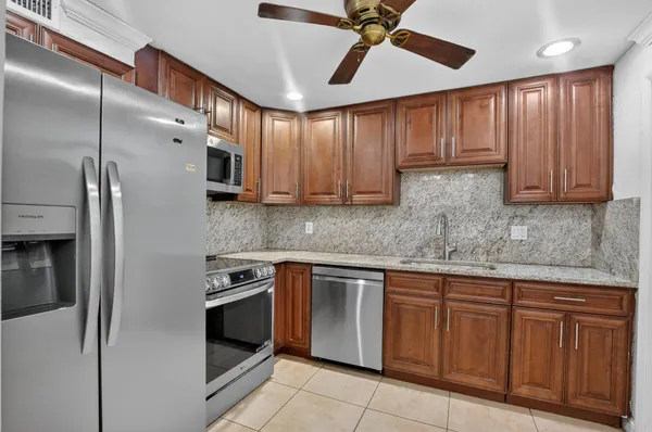 a kitchen with stainless steel appliances granite countertop a refrigerator a sink dishwasher and wooden cabinets