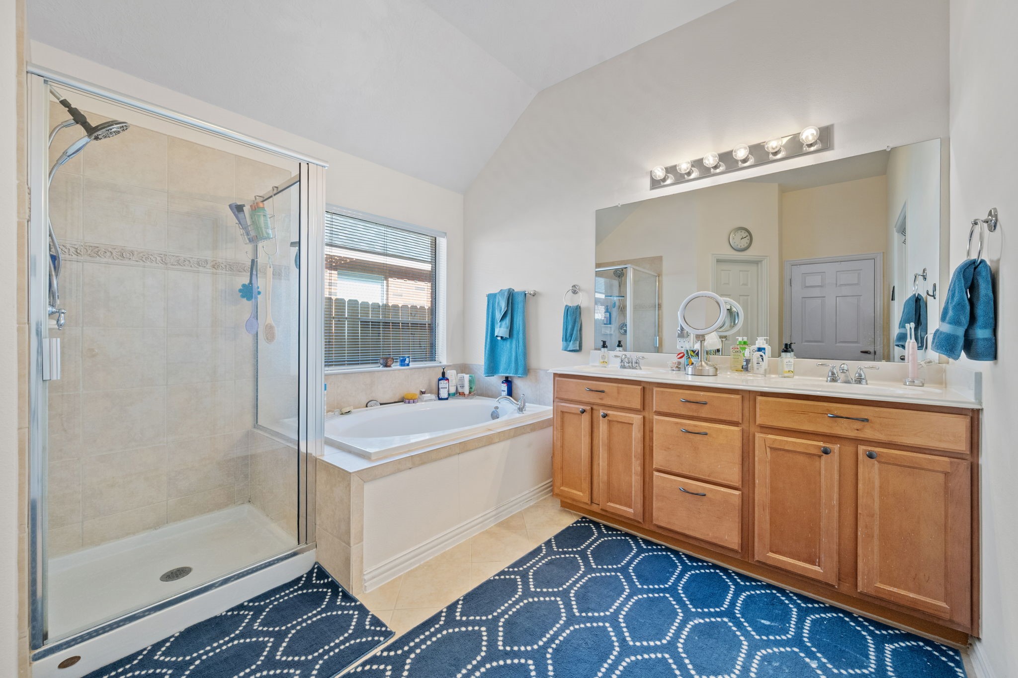 31419 Fountainbrook Park Lane Spring, TX 77386 - Photo 16 of 28 This bathroom features a spacious layout with a glass-enclosed shower and a separate soaking tub. It includes a large double vanity with ample storage and a wide mirror. The room is well-lit and has a modern tile design.