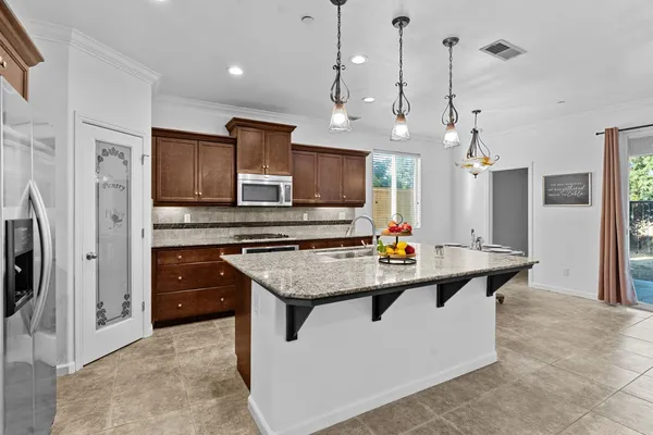 a kitchen with stainless steel appliances kitchen island granite countertop a sink and a refrigerator