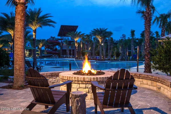 a patio with tables and chairs pool and a fire pit with wooden fence