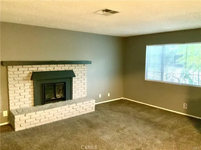 a view of an empty room with a fireplace and a window
