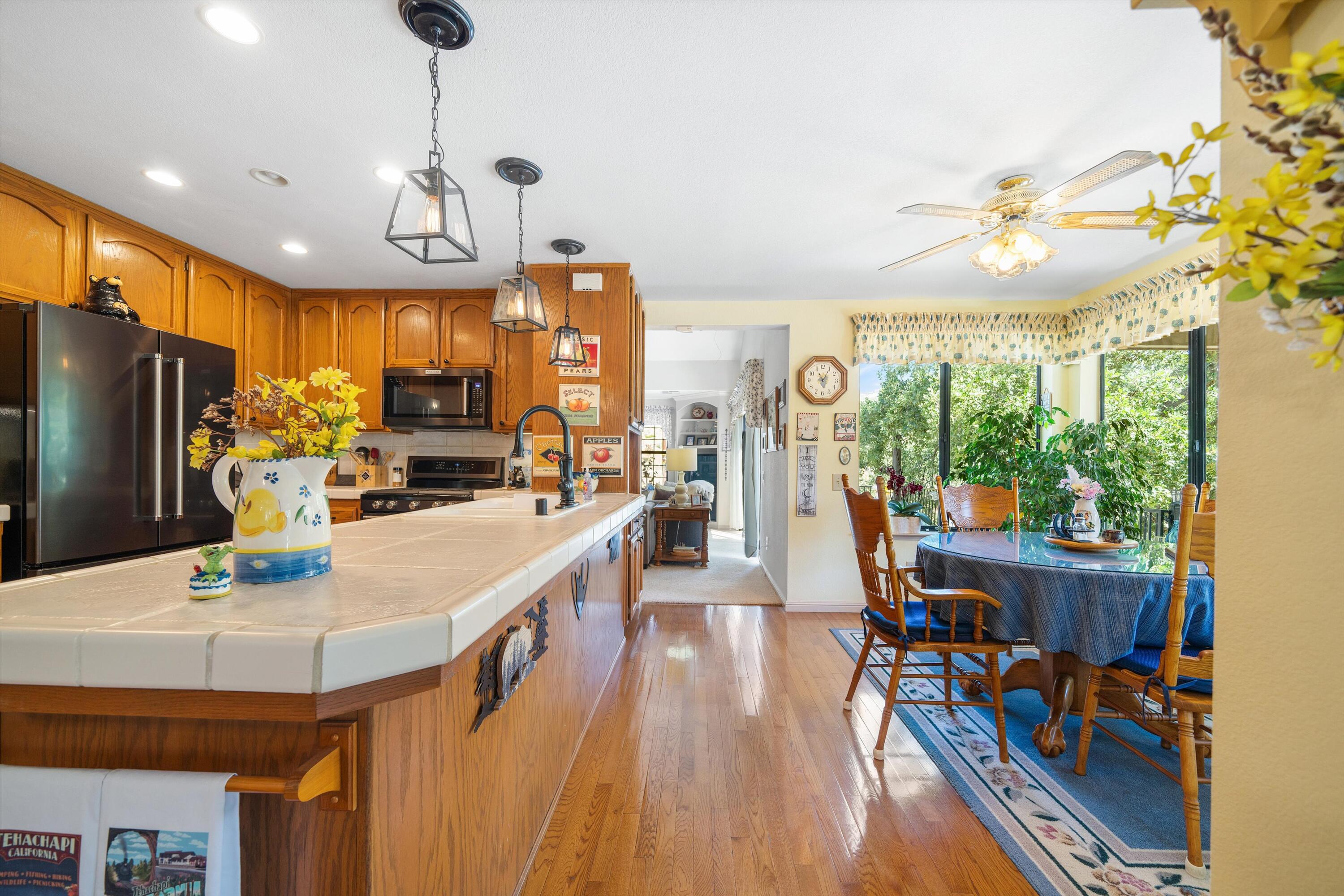 26460 Brian Place Tehachapi, CA 93561 - Photo 8 of 50 a kitchen with stainless steel appliances granite countertop a refrigerator a sink dishwasher a dining table and chairs with wooden floor