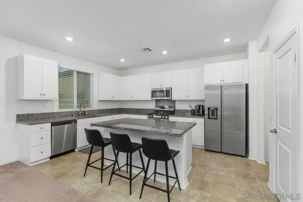 a kitchen with stainless steel appliances granite countertop a table chairs sink refrigerator and cabinets