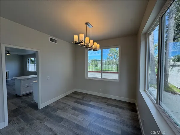 a room with wooden floor a chandelier and chair