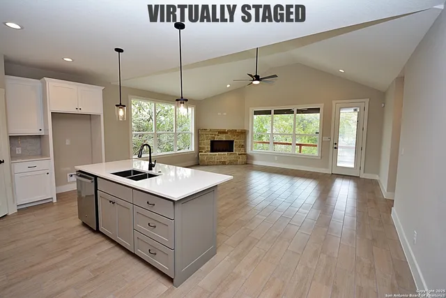 a large kitchen with stainless steel appliances granite countertop a large counter top a sink and a refrigerator