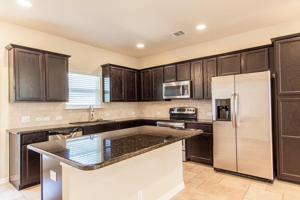 636 Lookout Tree Lane Round Rock, TX 78664 - Photo 8 of 23 a kitchen with stainless steel appliances granite countertop a sink stove microwave and refrigerator