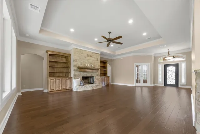 a view of a livingroom with a fireplace a ceiling fan and wooden floor