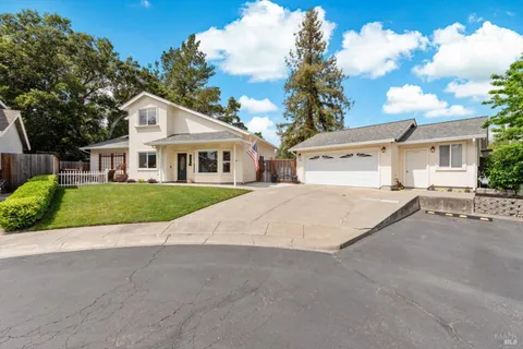 a view of a white house with a big yard plants and large trees