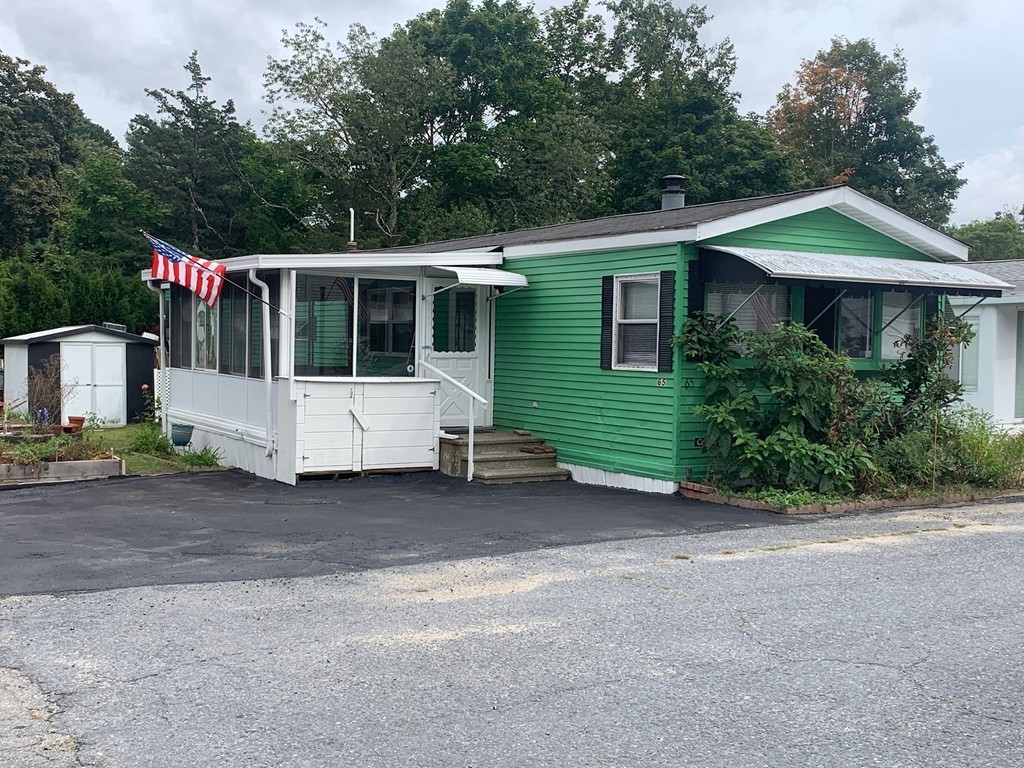 83 Clark Road, Unit 65 Shirley, MA 01464 - Photo 1 of 15 a view of a house with a small yard and a large tree