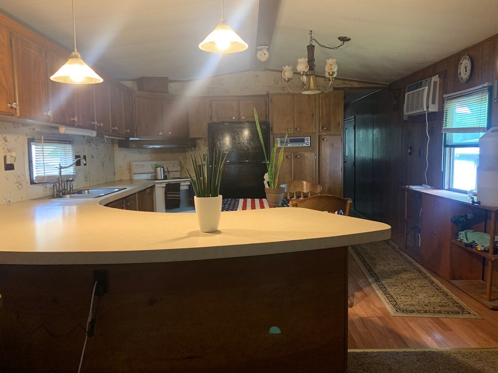 83 Clark Road, Unit 65 Shirley, MA 01464 - Photo 9 of 15 a large kitchen with kitchen island a sink stainless steel appliances and cabinets