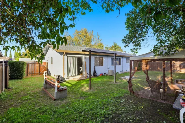 a view of a backyard with table and chairs potted plants and a large tree
