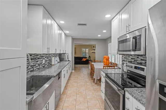 a kitchen with stainless steel appliances kitchen island granite countertop a stove and a sink
