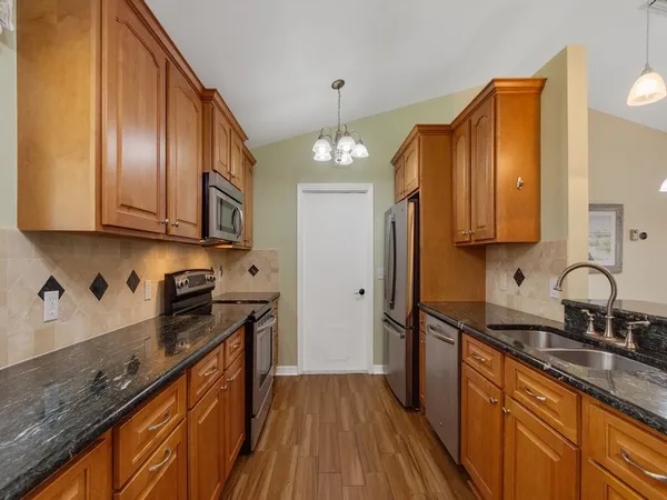 a kitchen with stainless steel appliances granite countertop wooden cabinets a stove a sink and dishwasher