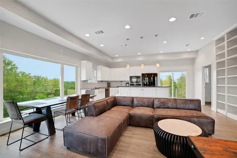 a kitchen with stainless steel appliances granite countertop a refrigerator a sink dishwasher a oven and a dining table with wooden floor