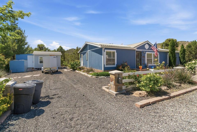 327 North Lodge Road Central, UT 84722 - Photo 2 of 45 Blue exterior residence with white trim, featuring a gravel driveway, white picket fence, and established landscaping