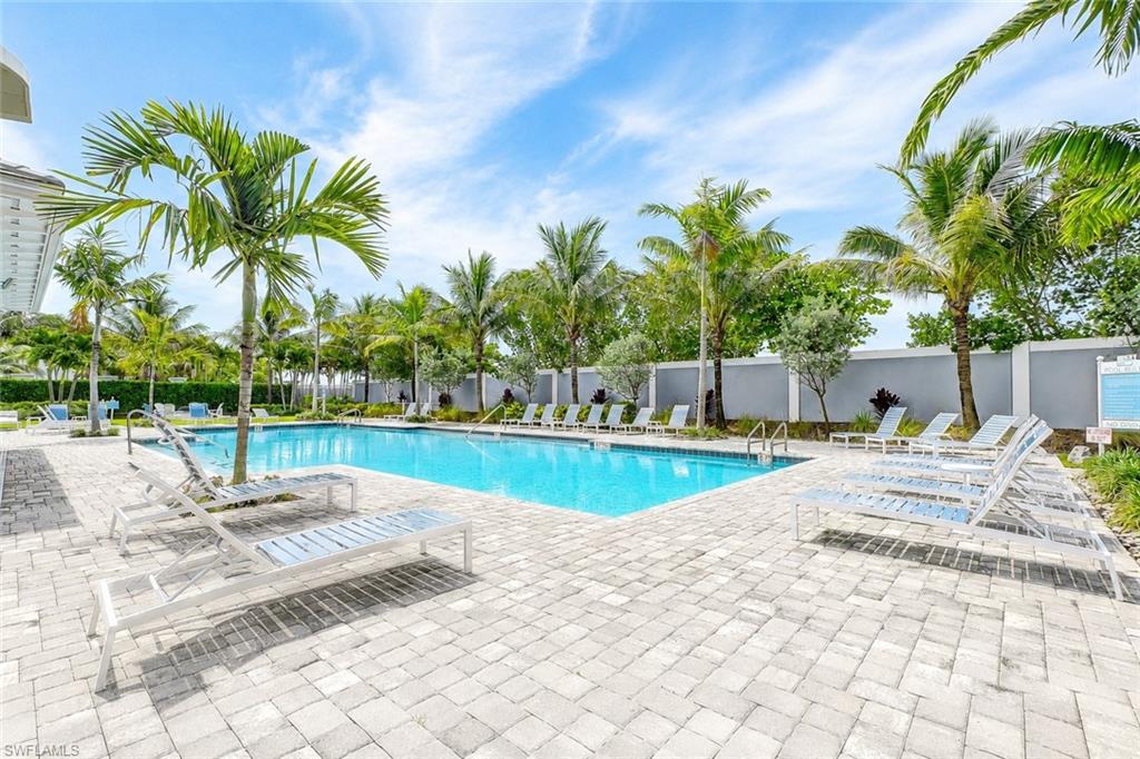 2620 Seychelles Circle, Unit 1302 Naples, FL 34112 - Photo 34 of 43 a view of a swimming pool with a lounge chair and palm trees