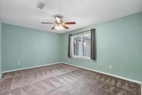 an empty room with a window and a fan