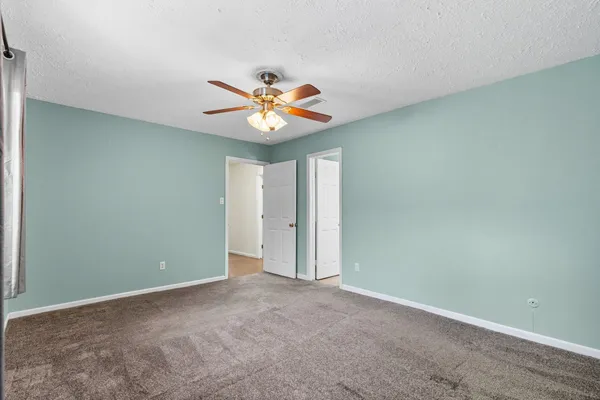 an empty room with a window and a fan